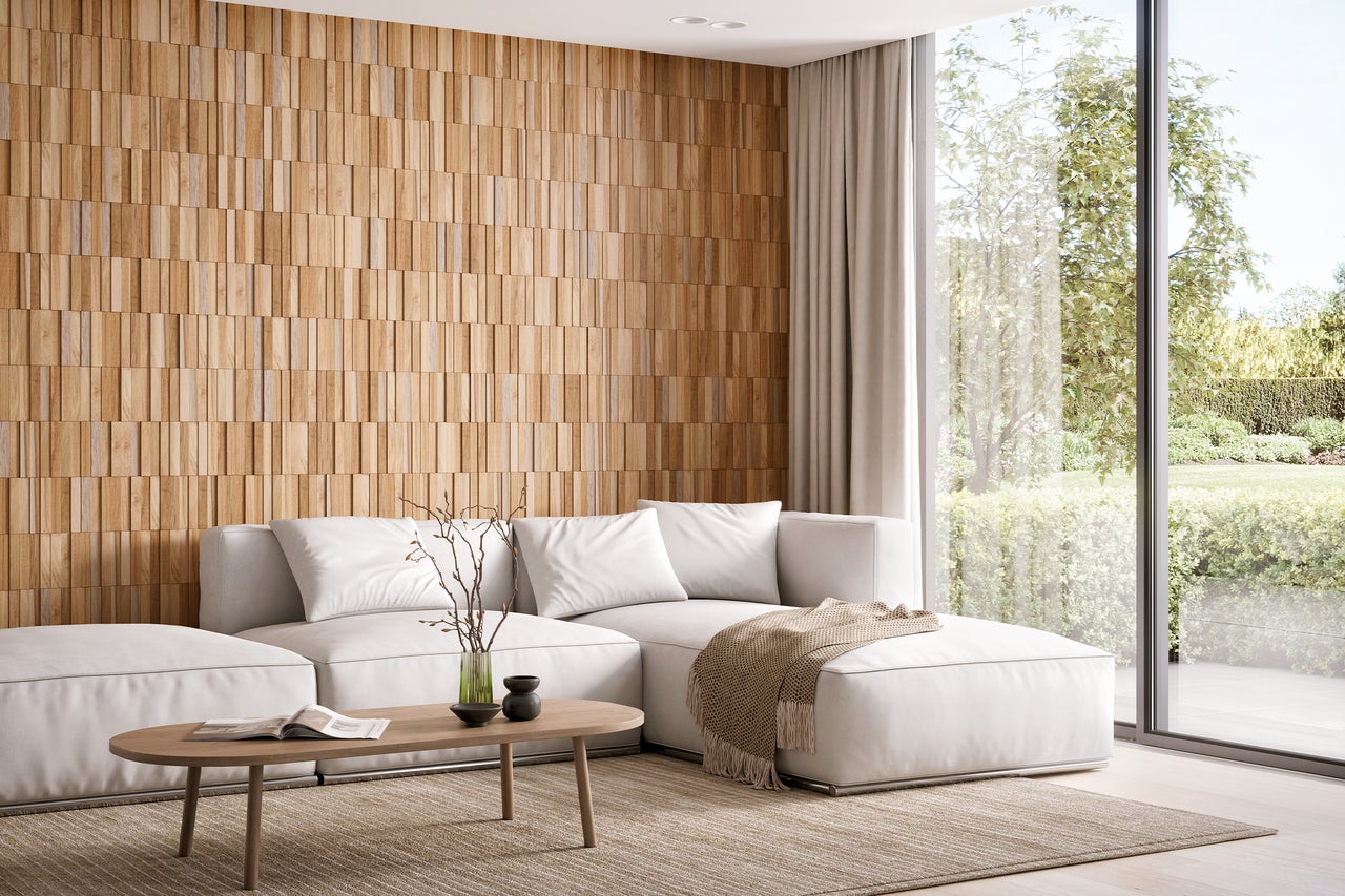 Lichte woonkamer met houten wand, bank en uitzicht op de tuin