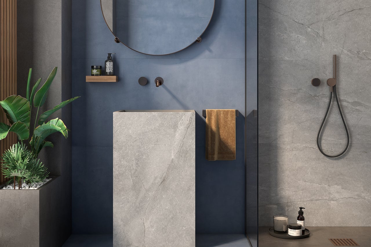 Moderne badkamer met vrijstaande wastafel, ronde spiegel, handdoek en douchearmatuur.