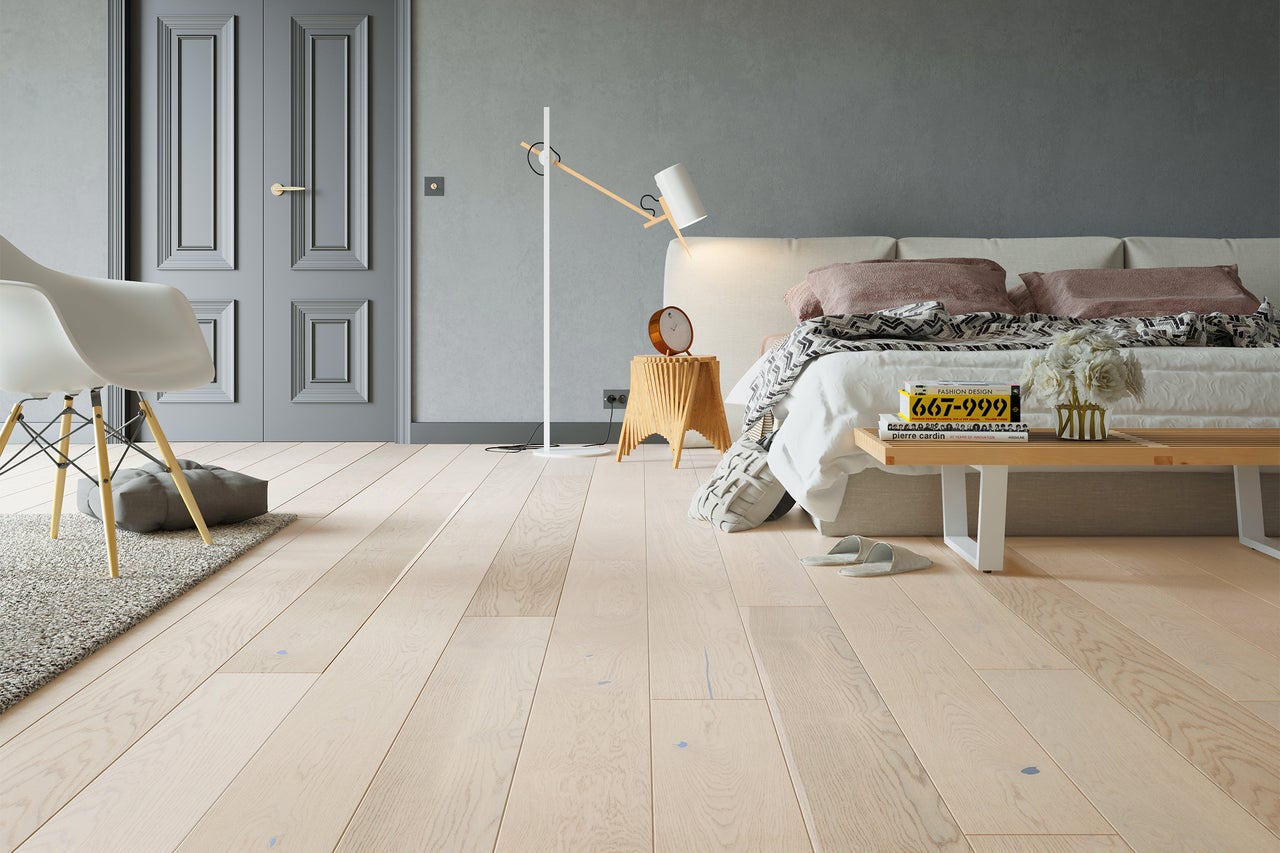 Slaapkamer met bed, lamp, stoel en houten vloer
