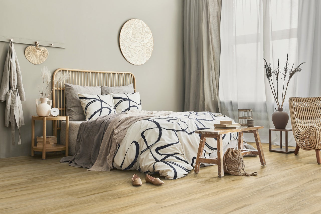 Lichte slaapkamer met houten vloer, rotan decoratie en een bed met bedrukt beddengoed