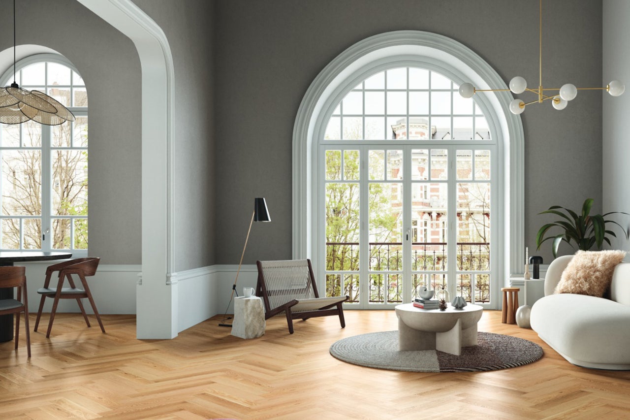 Lichte woonkamer met houten vloer, groot raam en moderne meubels