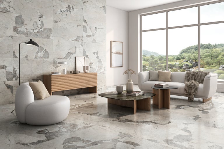 Lichte woonkamer met marmerlook tegels, bank en fauteuil