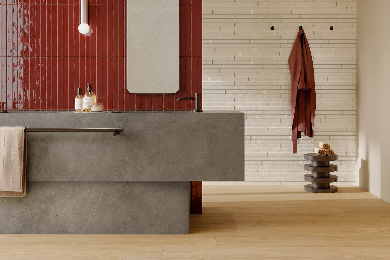 Moderne badkamer met rode en lichte wandtegels, wastafel en spiegel.
