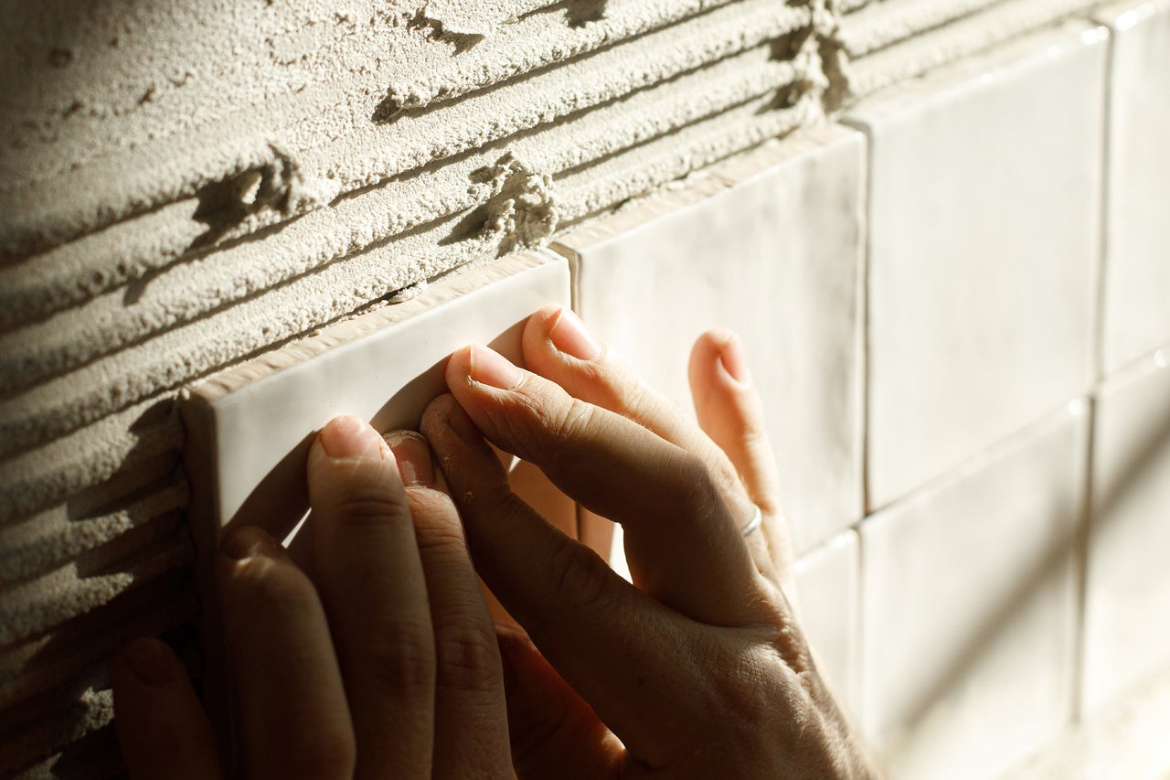 Hand bij het leggen van wandtegels