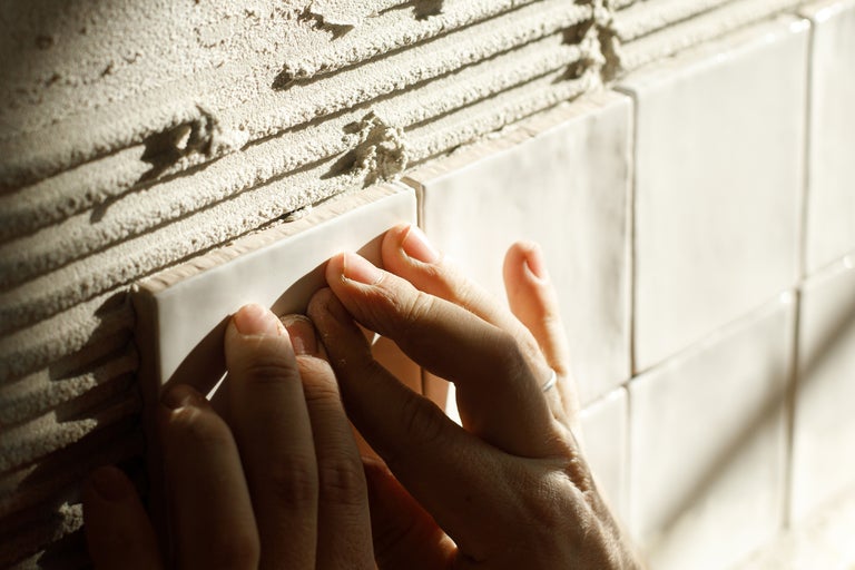 Hand bij het leggen van wandtegels