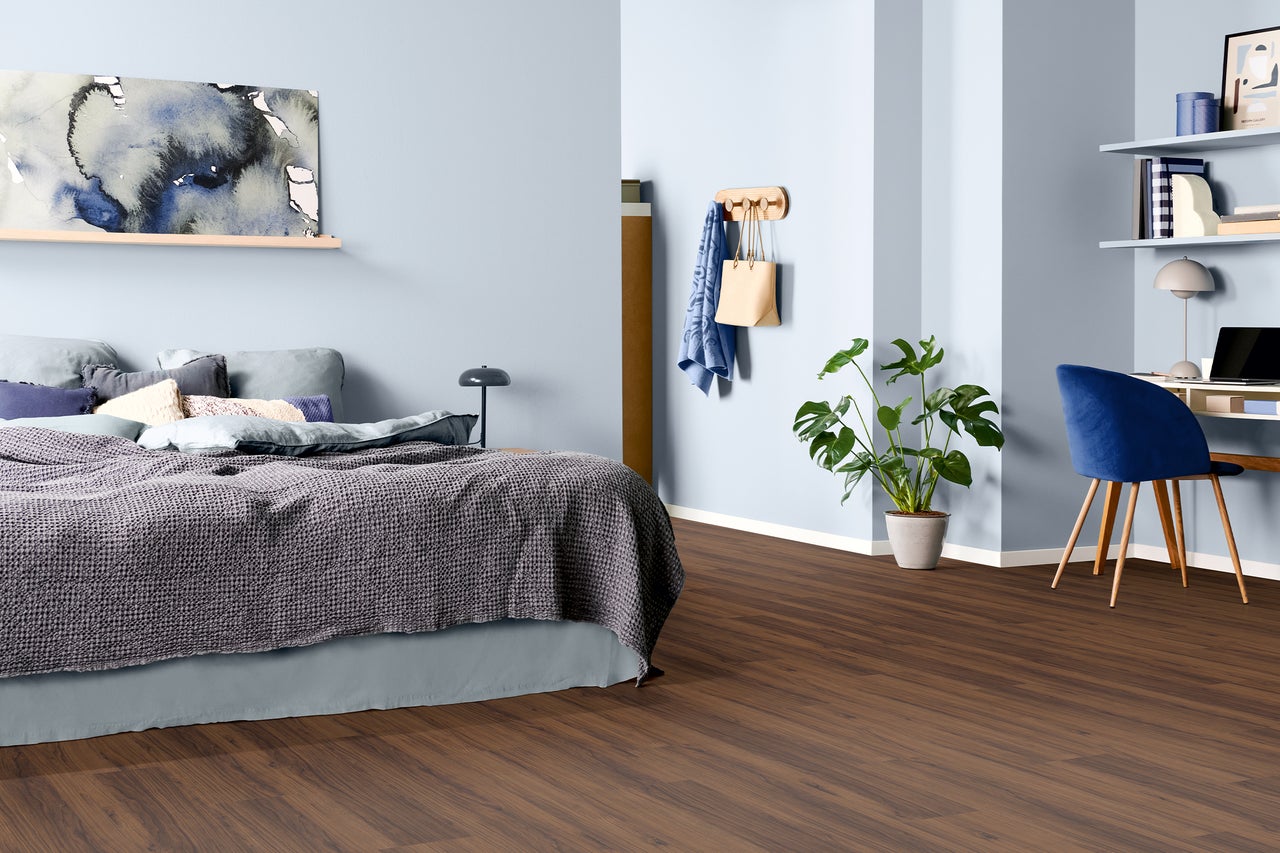 Slaapkamer met bed, bureau en bruine laminaatvloer