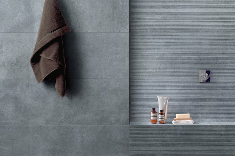 Moderne badkamer met grijze tegels, handdoek, zeep en huidverzorgingsproducten op een plank