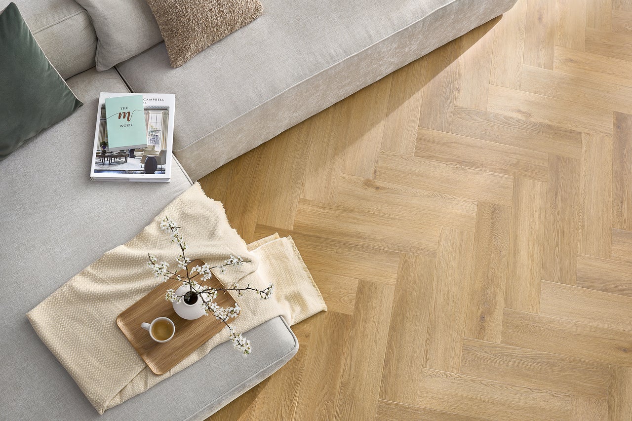 Afbeelding van een woonkamer met visgraatparket, bank en decoratie