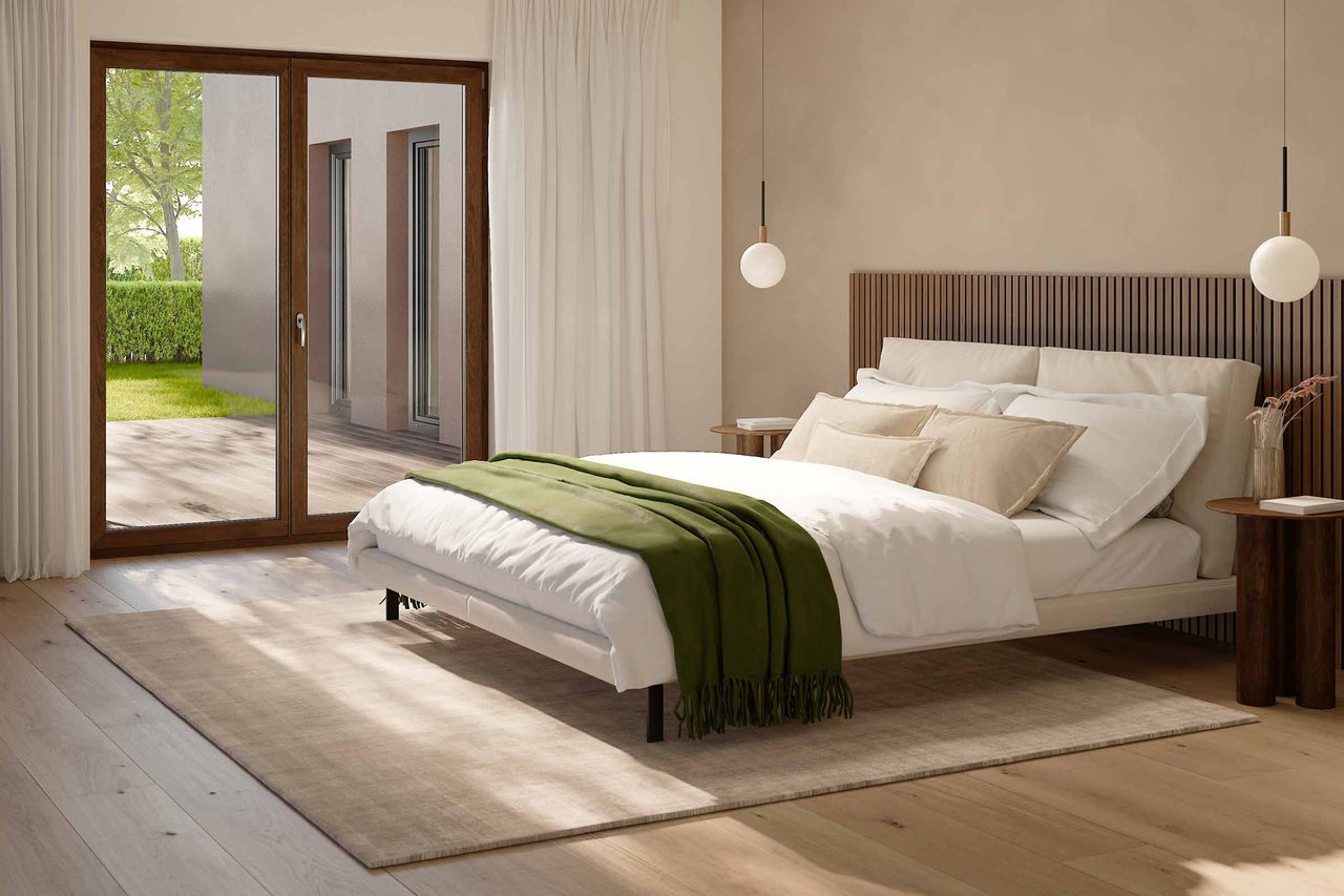 Lichte slaapkamer met bed, nachtkastjes, vloerkleed en openslaande deuren naar het terras
