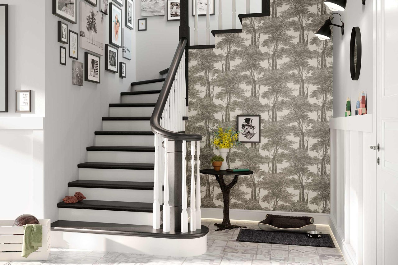 Hal met trap, gedecoreerd met behang, schilderijen en accessoires.