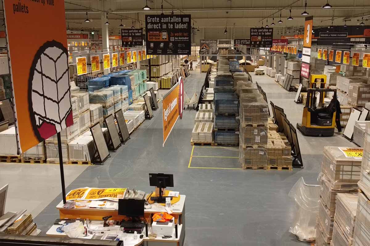 Overzicht van een Hornbach-winkel met tegels op pallets en een vorkheftruck.