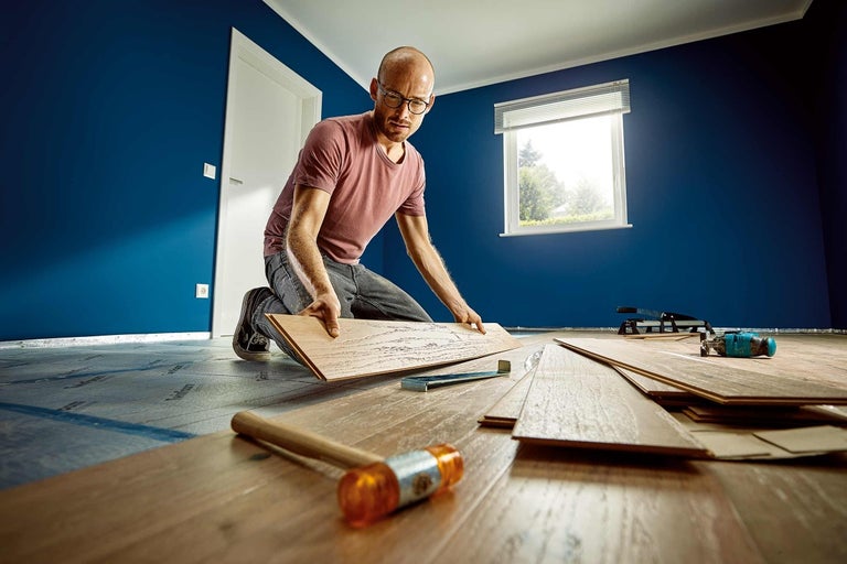 Man legt laminaatvloer in kamer met gereedschap