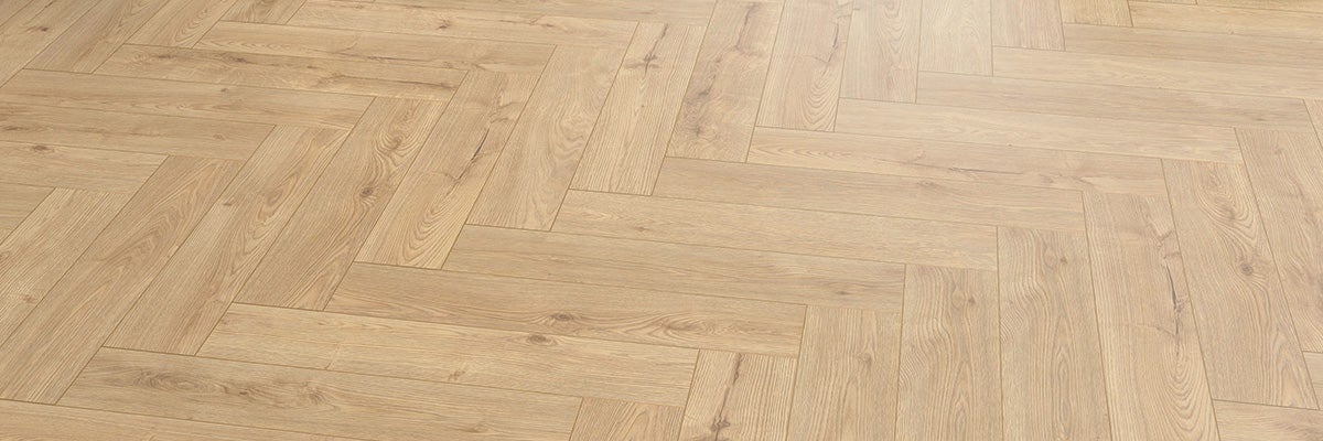 Houten laminaatvloer met visgraatpatroon in eikenlook.