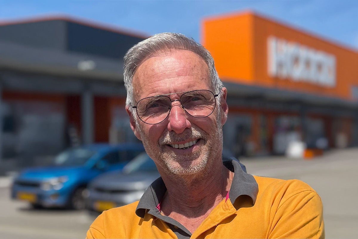 Een man met een bril glimlacht voor een Hornbach bouwmarkt.
