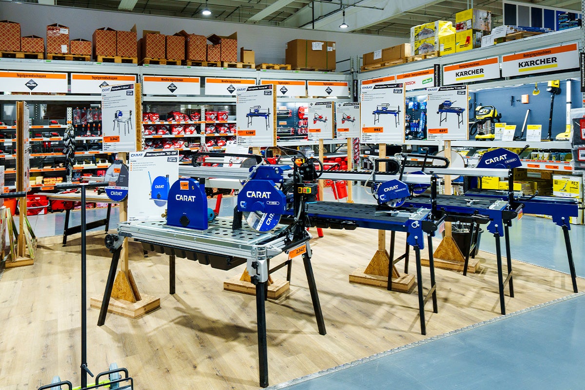 Georganiseerde verkoopruimte met Carat tegel- en steenzaagmachines op stabiele onderstellen, prijsborden en Kärcher Logo.