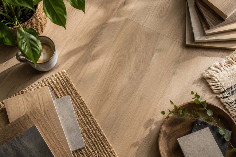 Lichte vloer met houtlook in een lichte kamerinrichting met verschillende materiaalmonsters, een kamerplant en een kopje koffie.