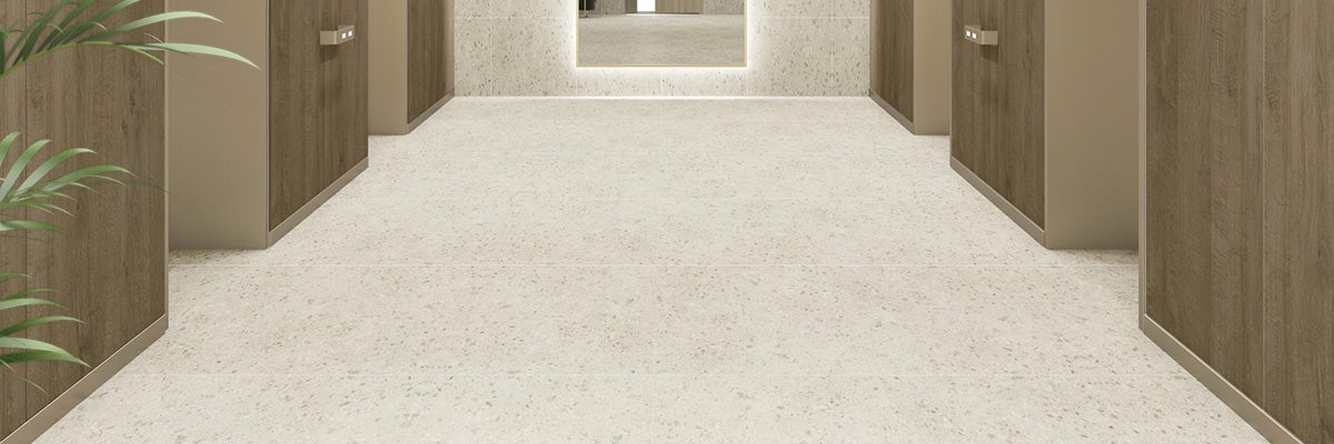 Moderne vloertegels in terrazzo look gelegd in een hal met wandbekleding in houtlook.