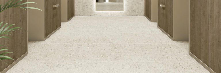 Moderne vloertegels in terrazzo look gelegd in een hal met wandbekleding in houtlook.
