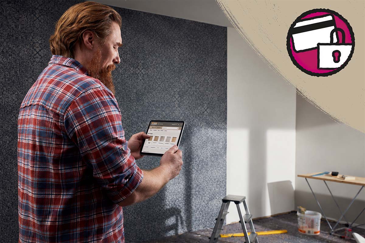Man gebruikt tablet voor productselectie in een gerenoveerde kamer met behang met patroon en symbool voor veilig betalen.