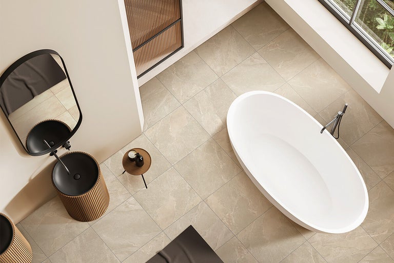 Moderne badkamer met vrijstaand bad en wastafel op tegelvloer met natuursteenlook in bovenaanzicht.