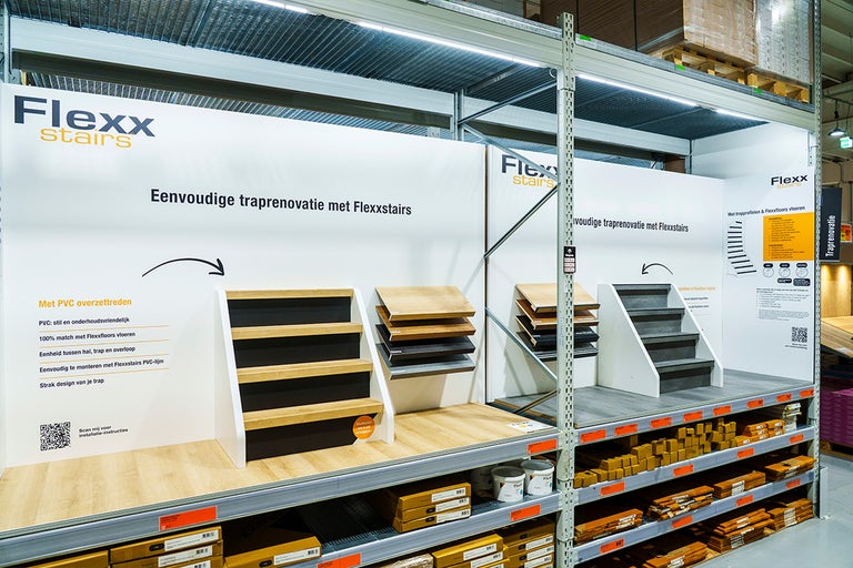 Flexx stairs verkoopdisplay voor traprenovatie met overzettreden en materiaalmonsters in een lichte, georganiseerde winkelstelling.