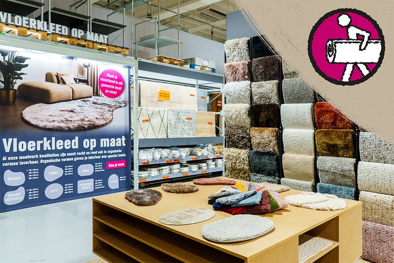 Afdeling voor vloerkleden op maat met een monstertafel voor verschillende vormen en kleuren en een wand met diverse tapijtstalen in de winkel.