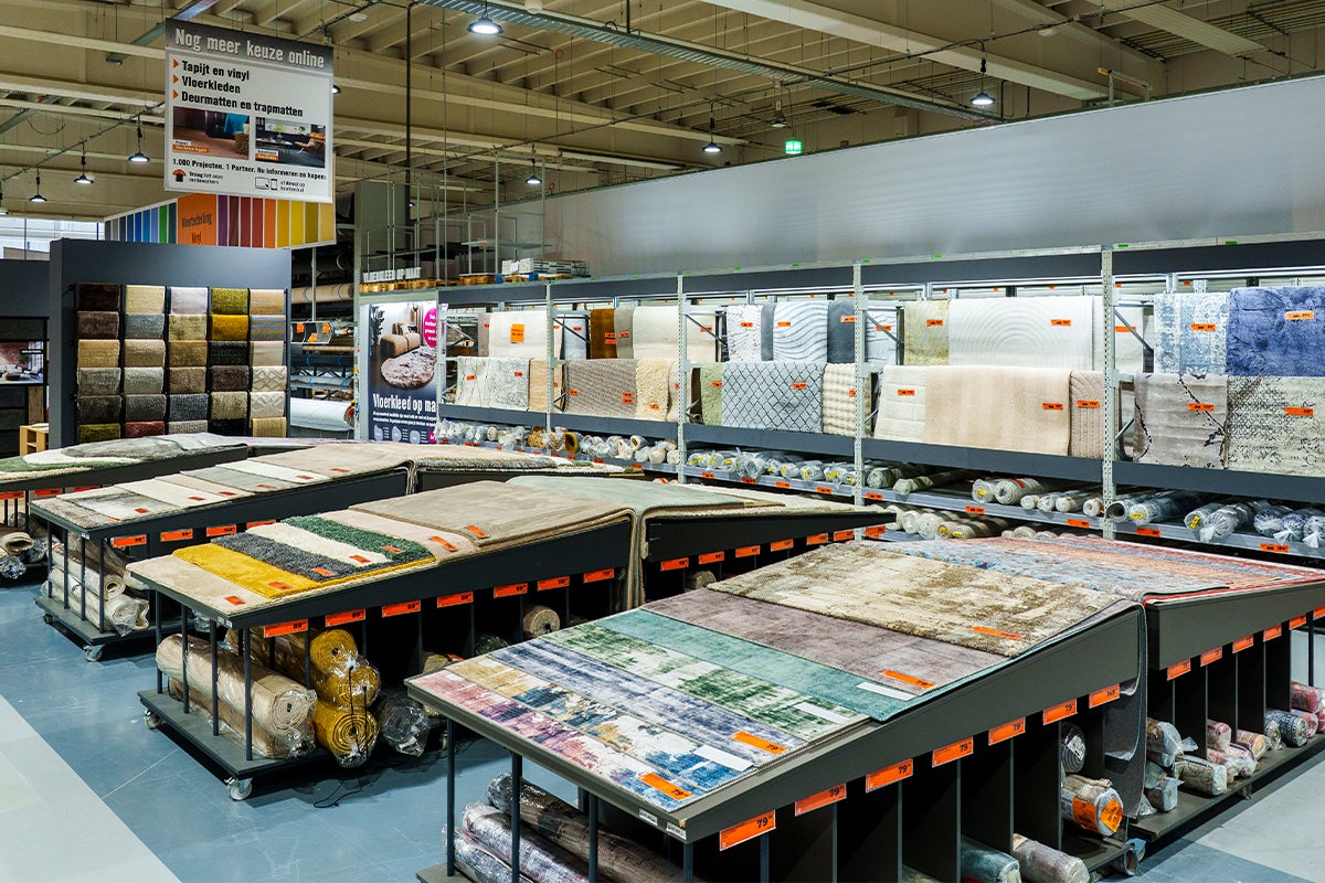 Overzichtelijke showroom met een ruim assortiment aan vloerkleden en tapijten in diverse motieven en materialen op stellingen en tafels.