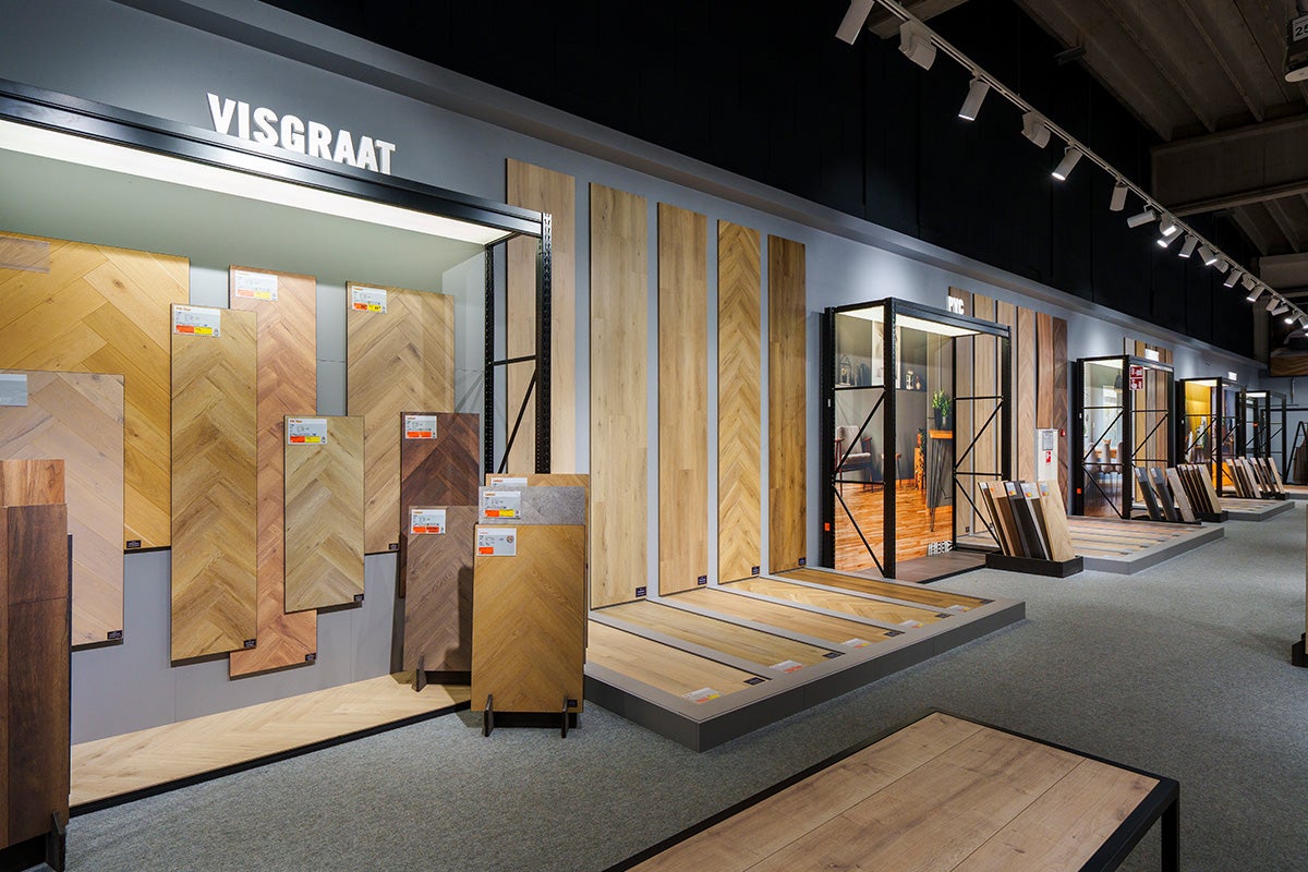 Helder verlichte showroom voor vloerbedekking met stalen van visgraatparket, laminaat en PVC in houtlook.
