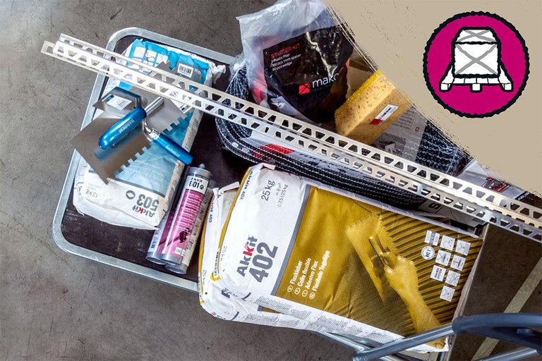 Tegeltoebehoren op een wagen: zakken tegellijm, lijmkammen, tegelprofielen, spons en afdichtingsmiddelen voor tegelprojecten.