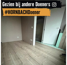 Een lichte kamer met laminaatvloer en behang met motief.