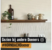 Plank met decoratie aan een wand met witte, langwerpige tegels