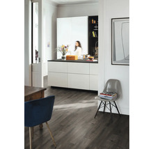 Lichte kamer met keuken, eettafel en stoel op donkere houten vloer.