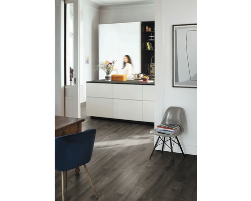 Lichte kamer met keuken, eettafel en stoel op donkere houten vloer.
