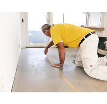 Man plakt afplakband op een vloer voor renovatiewerkzaamheden.