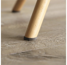 Detailopname van een stoelpoot met viltglijder op een houten vloer