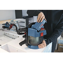 Een persoon plaatst een 18 Volt accu in een Bosch Professional accu stofzuiger GAS 18 Volt-1 in een werkplaats.