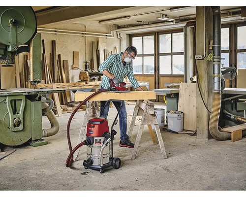 Ambachtman schuurt houten balk in werkplaats met Einhell nat droogzuiger verbonden aan Einhell Logo schuurmachine.