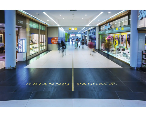 Interieur van de Johannis Passage met winkelpuien en mensen in een modern winkelcentrum.