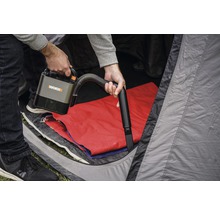 Een persoon gebruikt een draadloze WORX stofzuiger in een tent.