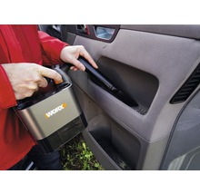 Persoon stofzuigt auto-interieur met snoerloze stofzuiger van het merk Worx