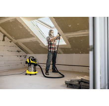 Man werkt met stofzuiger in een zolderkamer die wordt gerenoveerd.