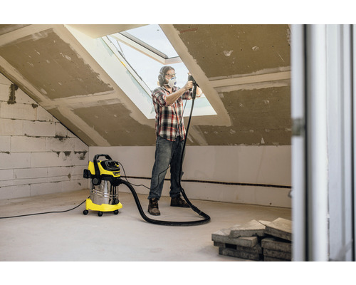Man werkt met stofzuiger in een zolderkamer die wordt gerenoveerd.
