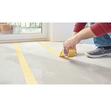 Persoon plakt schilderstape op een vloer.