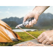 Persoon snijdt touw met een zakmes in de natuur.