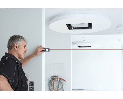 Ambachtsman meet een kamer met een laser afstandsmeter.