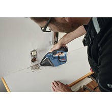 Een vakman zuigt bouwstof op een werkblad met een accustofzuiger.