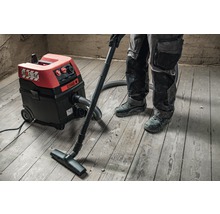 Industriële stofzuiger in gebruik op houten vloer.