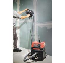 Man schuurt een wand met een gipsplaatschuurmachine die is aangesloten op een stofzuiger.