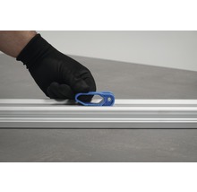 Een hand met beschermende handschoen bevestigt een blauwe schuif aan een aluminium rail.