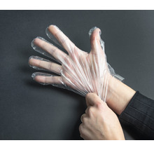 Een hand die een transparante wegwerphandschoen aantrekt